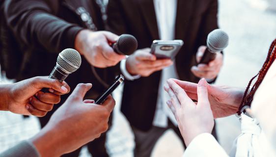 A group of people's hands holding microphones and recording equipment