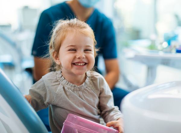 A toddler laughing, with a medical professional visible in the background