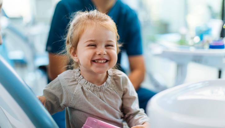 A toddler laughing, with a medical professional visible in the background