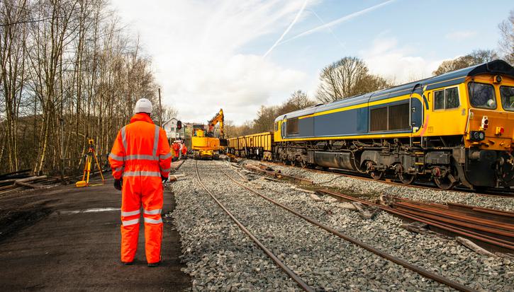 A railway engineer in hi-vis stands beside a track