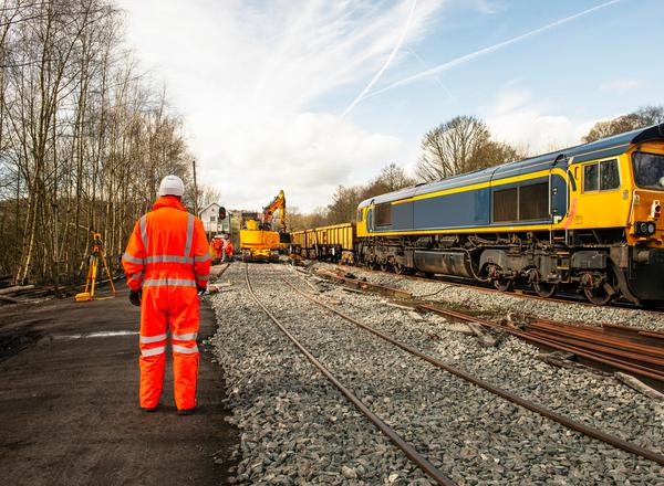 A railway engineer in hi-vis stands beside a track