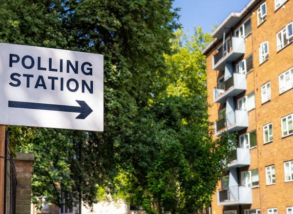 A sign for a polling station next to a block of flats