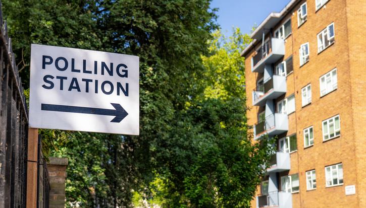 A sign for a polling station next to a block of flats