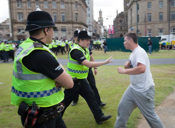 Police warn an aggressive member of the public, with more police visible in the background