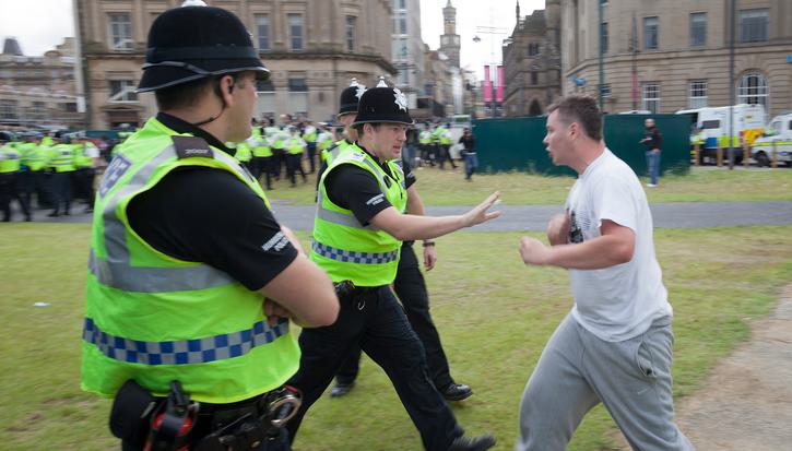 Police warn an aggressive member of the public, with more police visible in the background