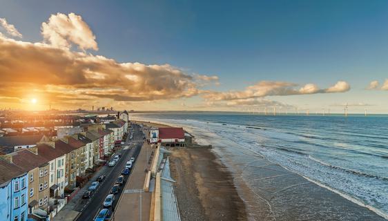 The sun sets behind a strip of colourful houses along the seafront